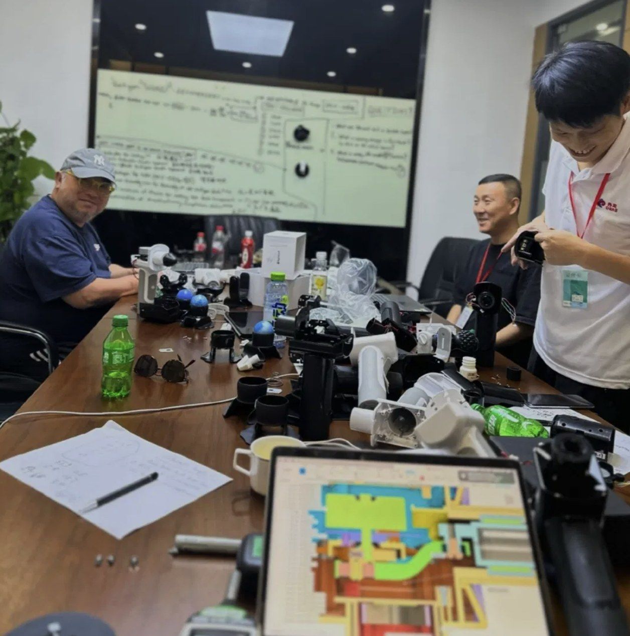 A meeting table covered in product prototypes, with a mould-flow analysis on a tablet.