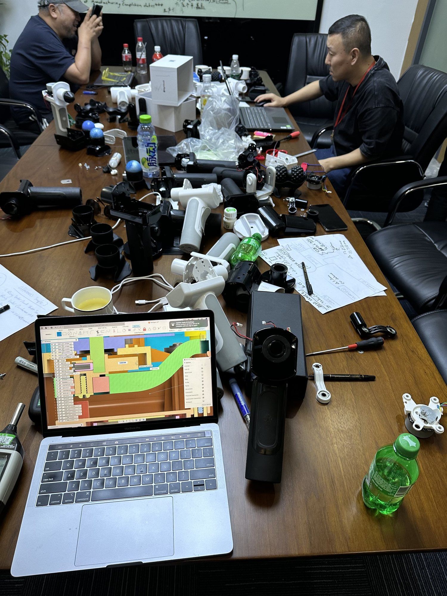 A meeting table covered in product samples, with a mould-flow analysis open on a laptop.