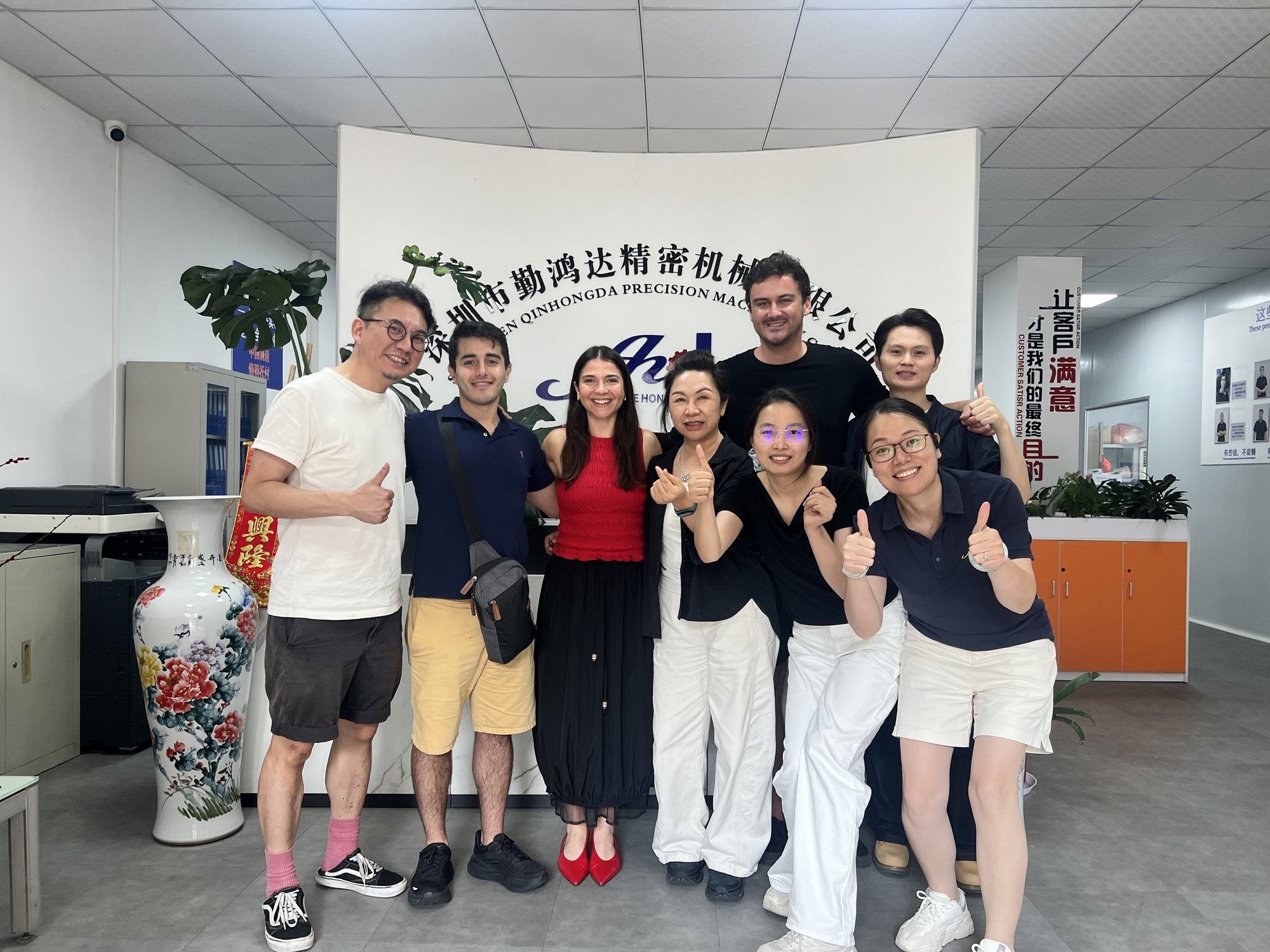 Curtis with founders and factory staff in a factory lobby, giving a thumbs up.