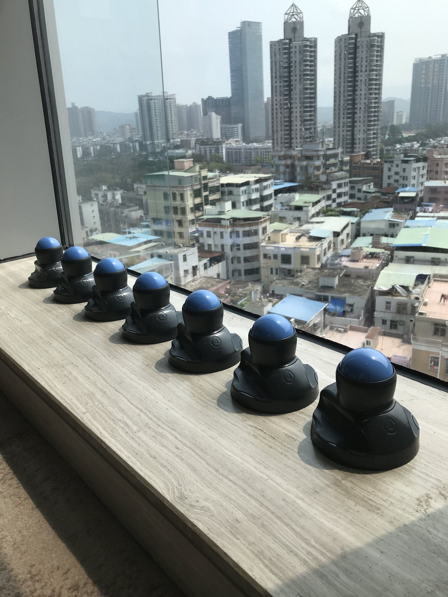 A row of Vertiball samples on a windowsill, with city towers behind.
