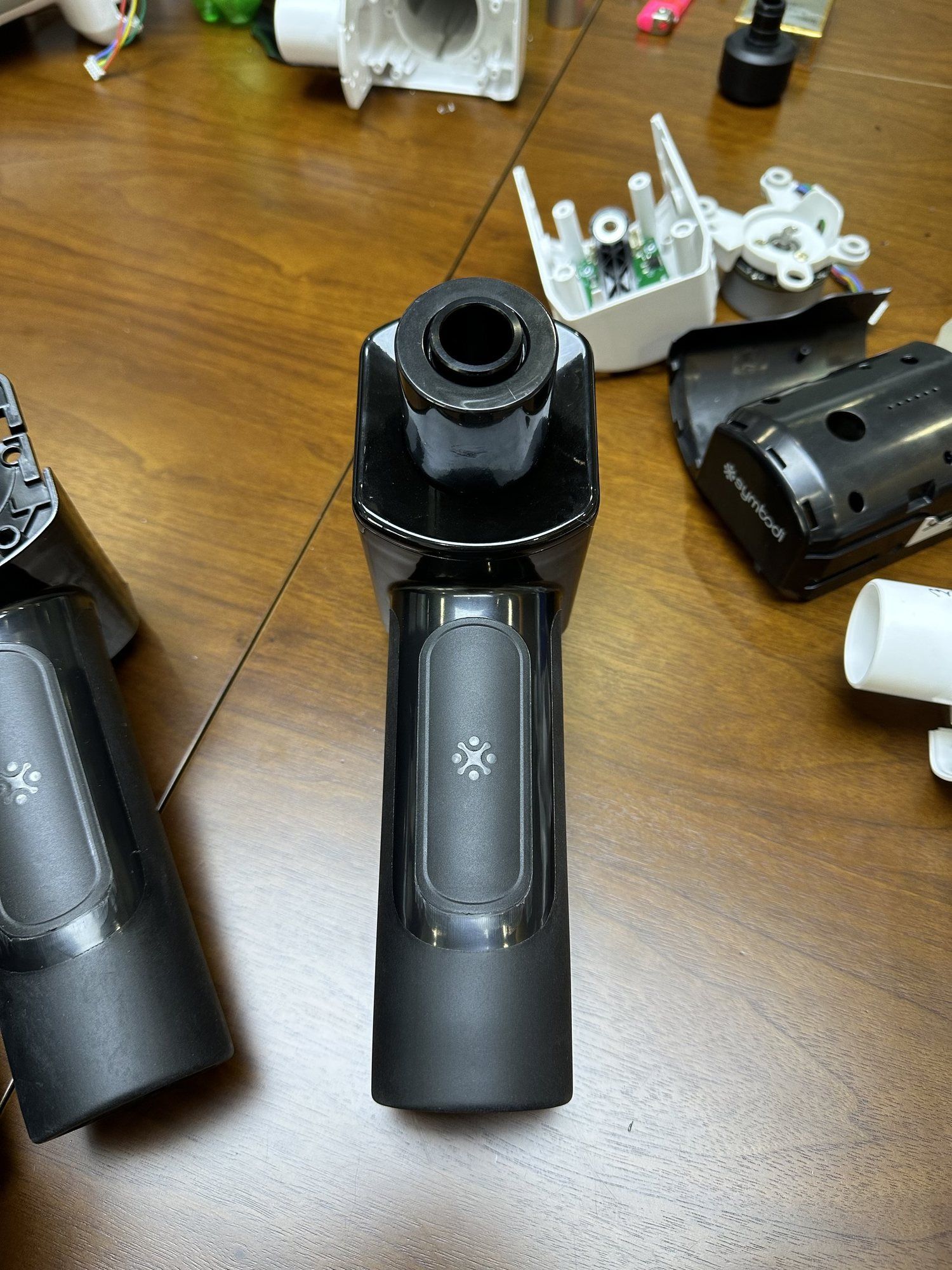 A black Vertigun production sample on a table beside open housings.